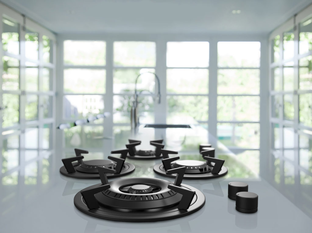 Four black burners on a white marble countertop